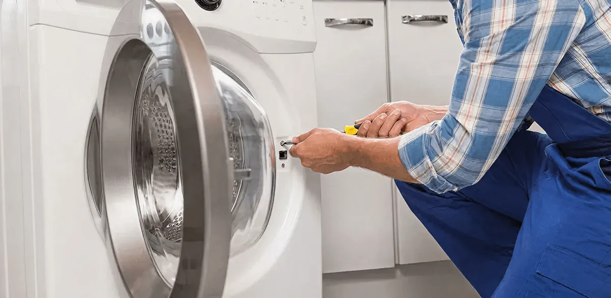 Handyman repairing a clothes dryer and checking electrical connections in Oakland, CA