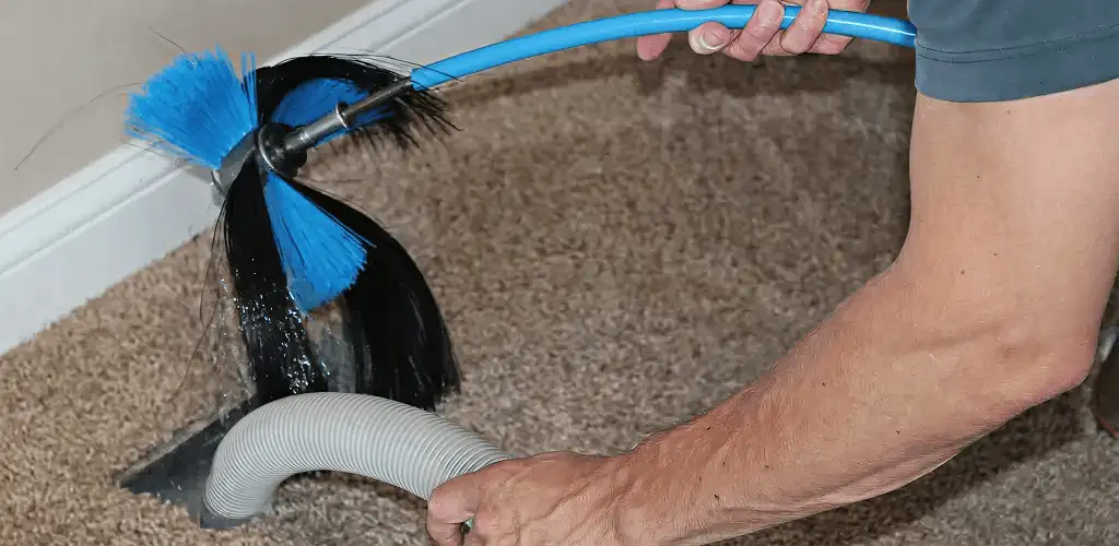Dryer vent cleaning technician brushing lint from a vent line in Oakland, CA