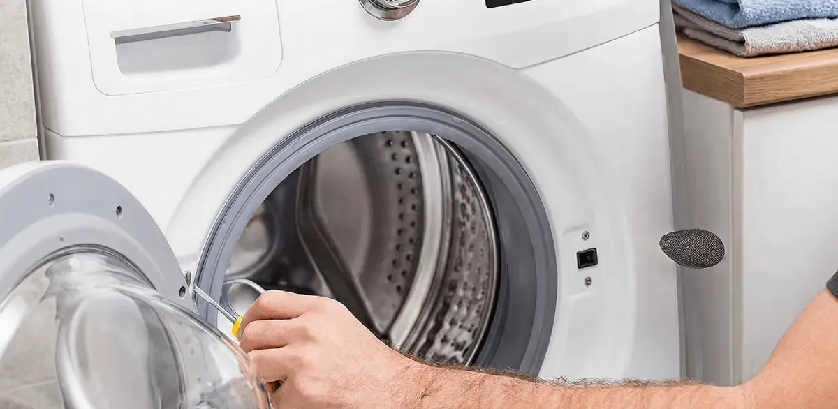 Handyman repairing a front-load washing machine and inspecting the drum in Oakland, CA